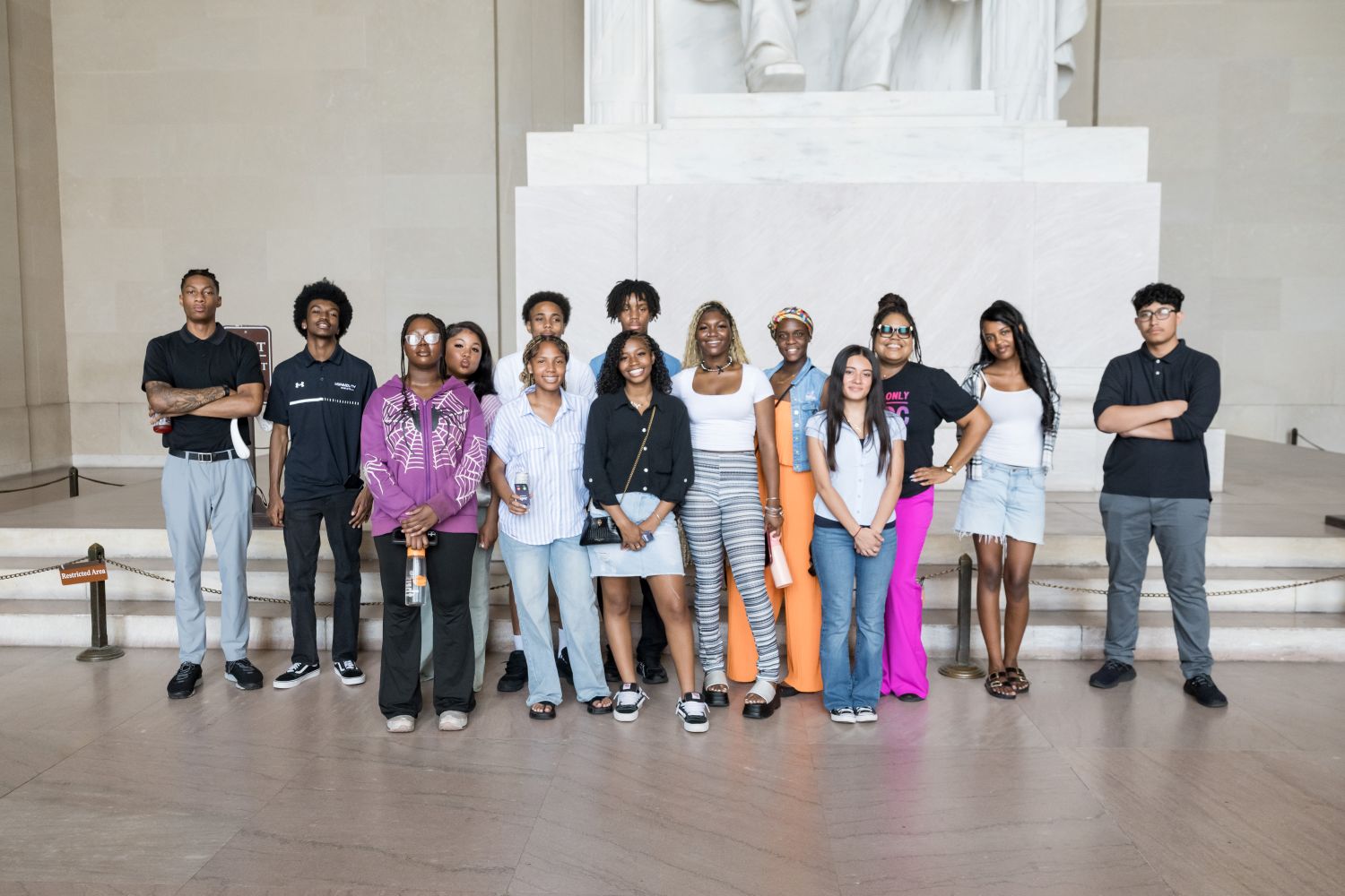 A group of teenagers stand in front of the Lincoln Memorial