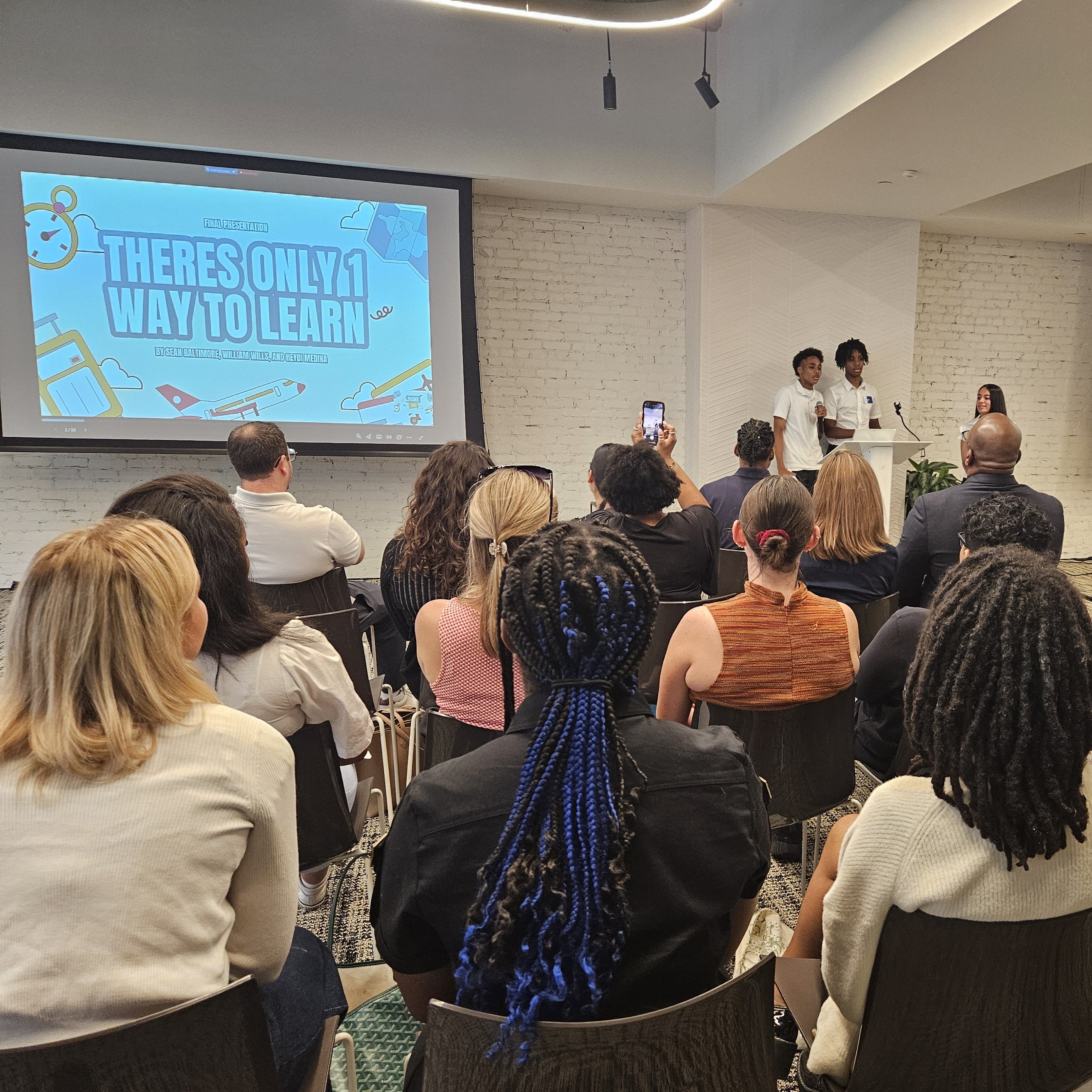 Three young people present in front a room of people