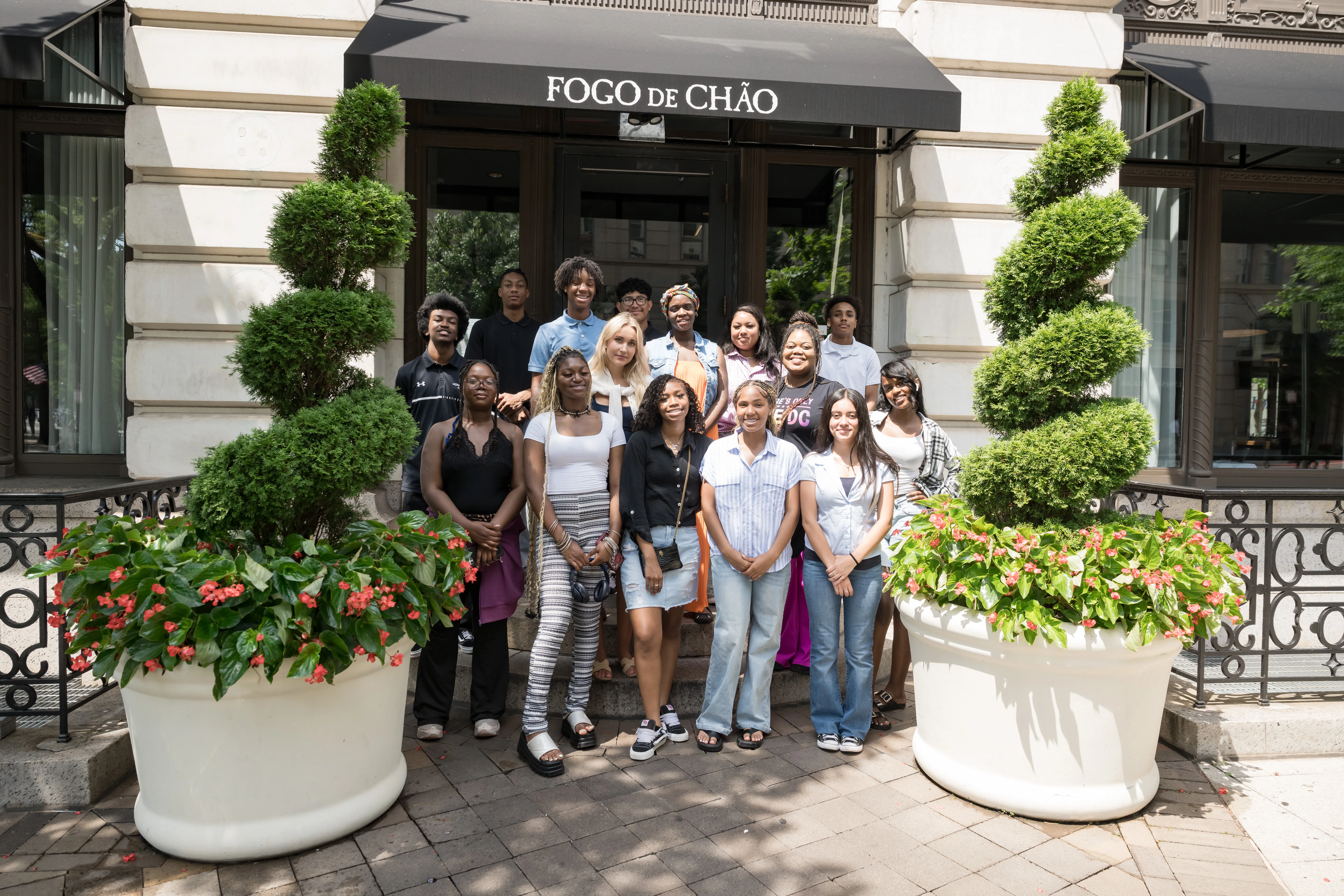 A group of Black and Brown high school interns stand in front of the Fogo de Chao Washington DC restaurant.