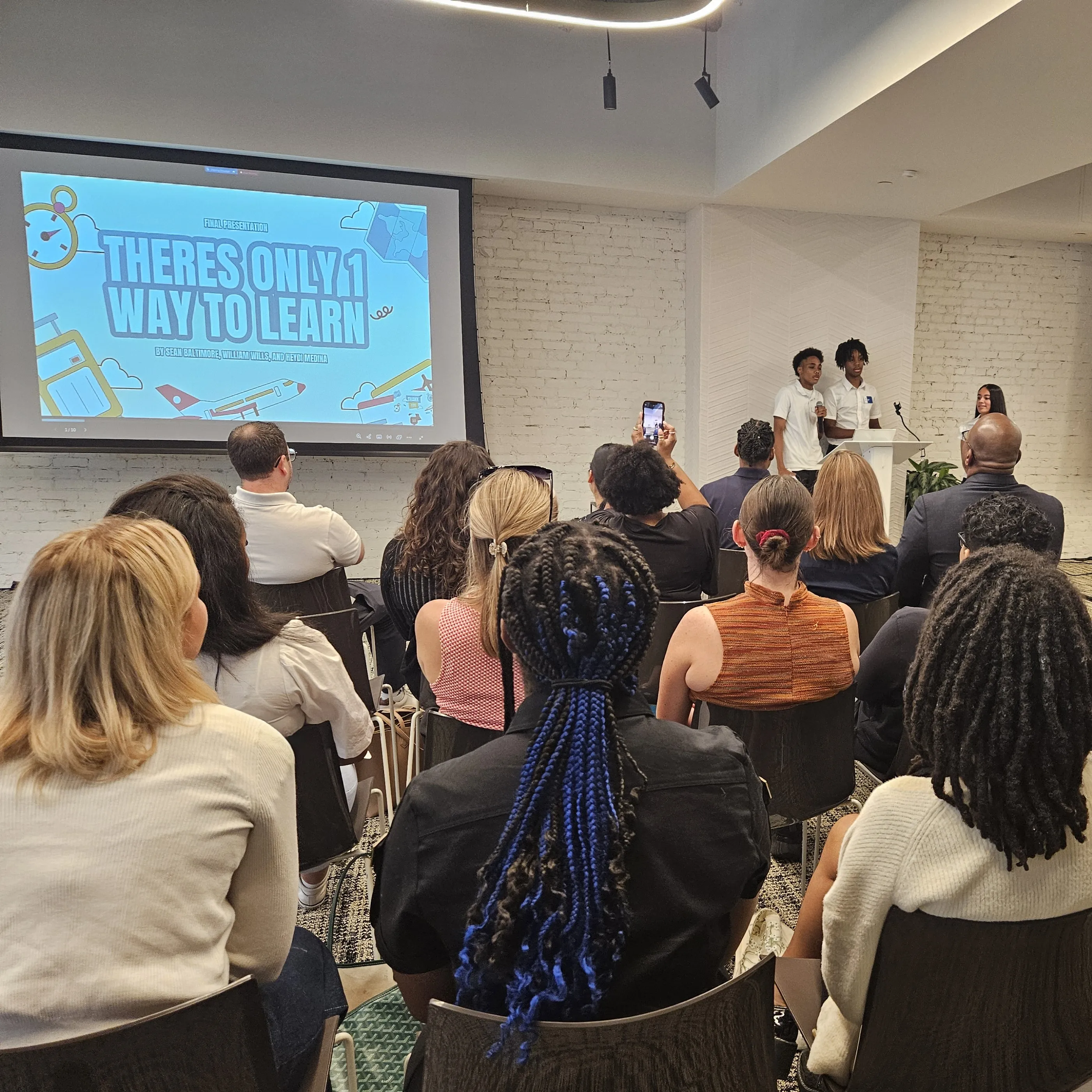 Three young people present in front a room of people